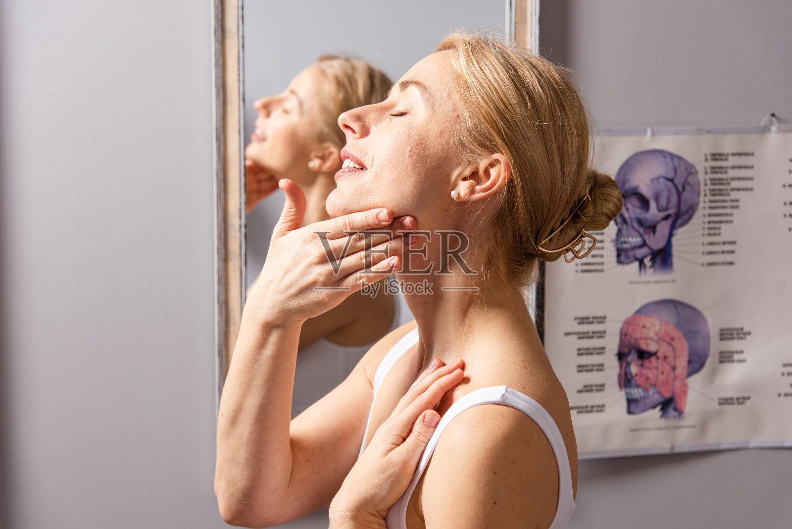 一名年轻女子在照镜子时做面部自我按摩，以达到提升和恢复活力的效果照片摄影图片