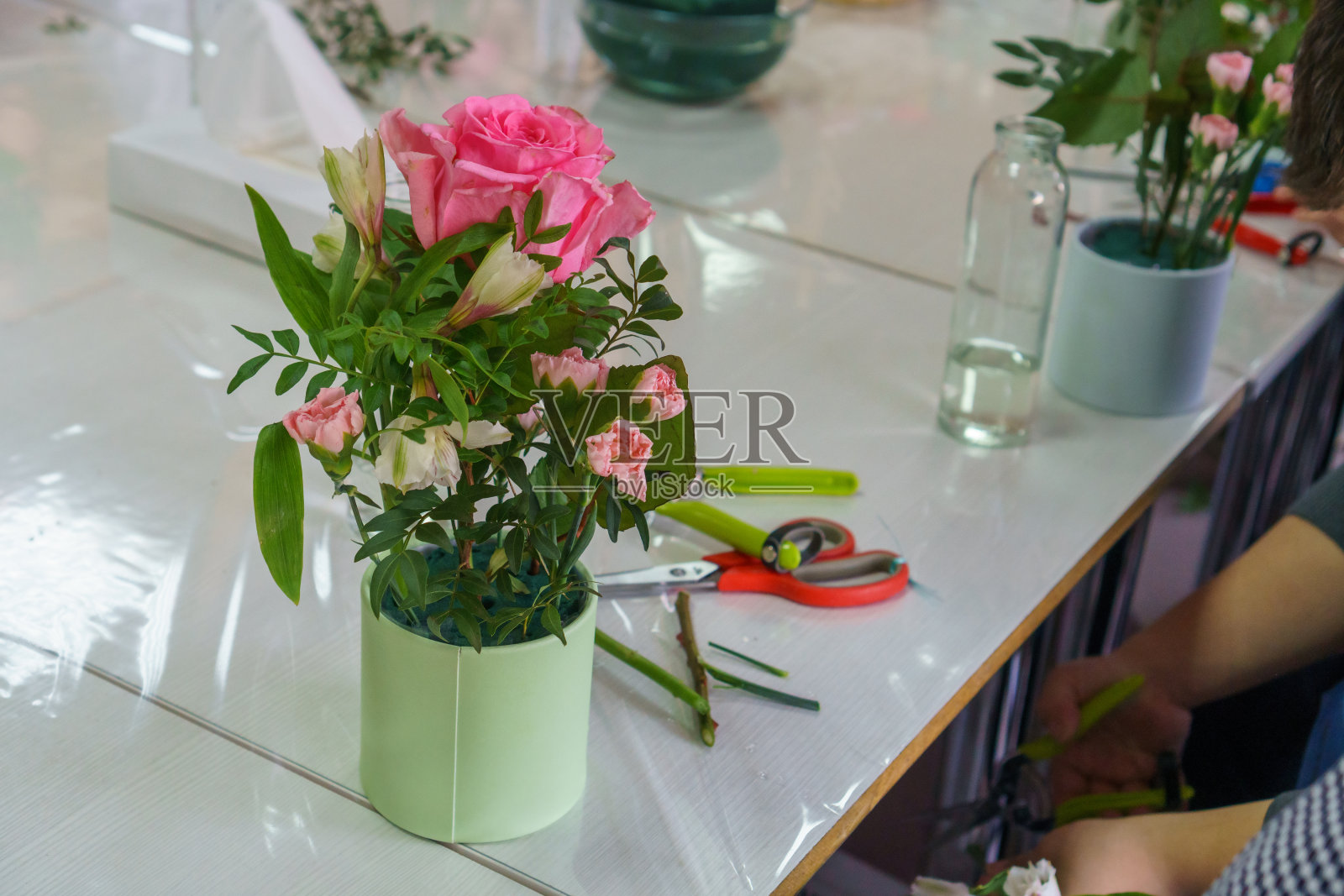 人们在一个大师班上制作盒子里的花束。没有脸，只有手和花束。照片摄影图片