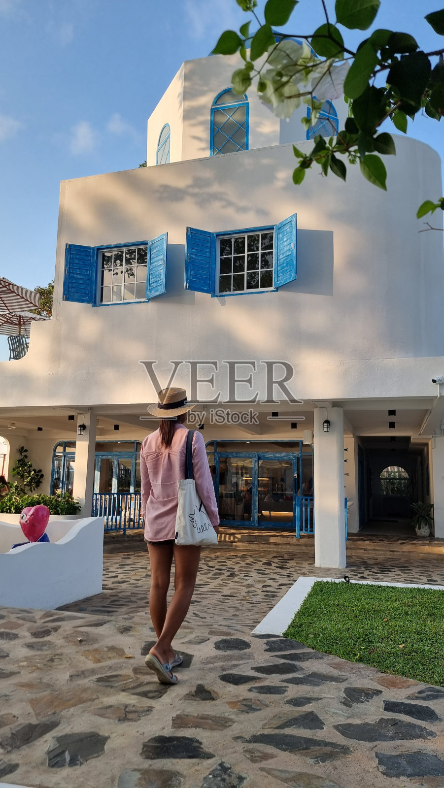 一个时髦的女人优雅地站在一栋洁白的建筑外,在建筑的背景下散发着自信和优雅照片摄影图片