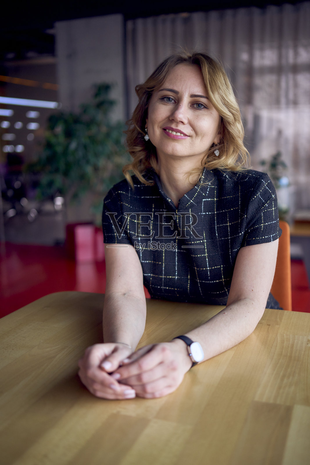 迷人的年轻成年女子在一个现代的咖啡馆酒吧坐在一张桌子照片摄影图片