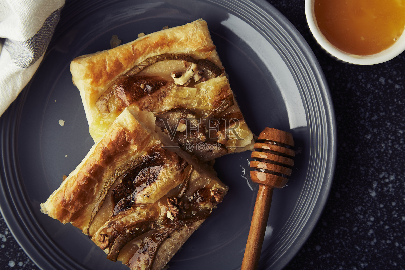 近距离拍摄新鲜的自制梨和蜂蜜糕点。酥皮挞配梨片，卡门培尔奶酪，蜂蜜，核桃照片摄影图片