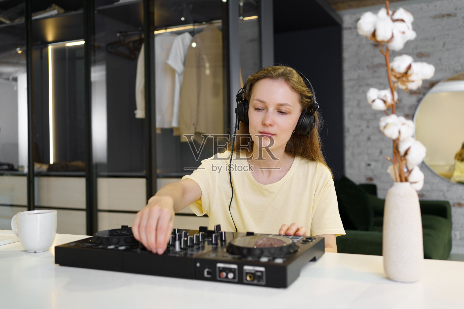 穿着黄色t恤、戴着耳机的年轻女DJ在房间里挑选、混音、听音乐。学习新事物的观念和爱好，各种职业照片摄影图片