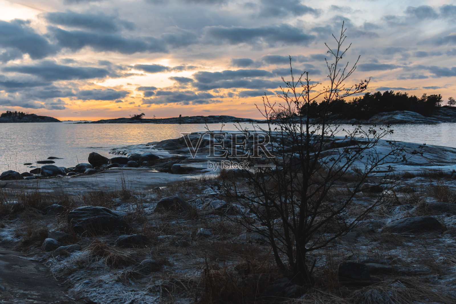 美丽的黄色日落，多云的天空，岩石海岸照片摄影图片