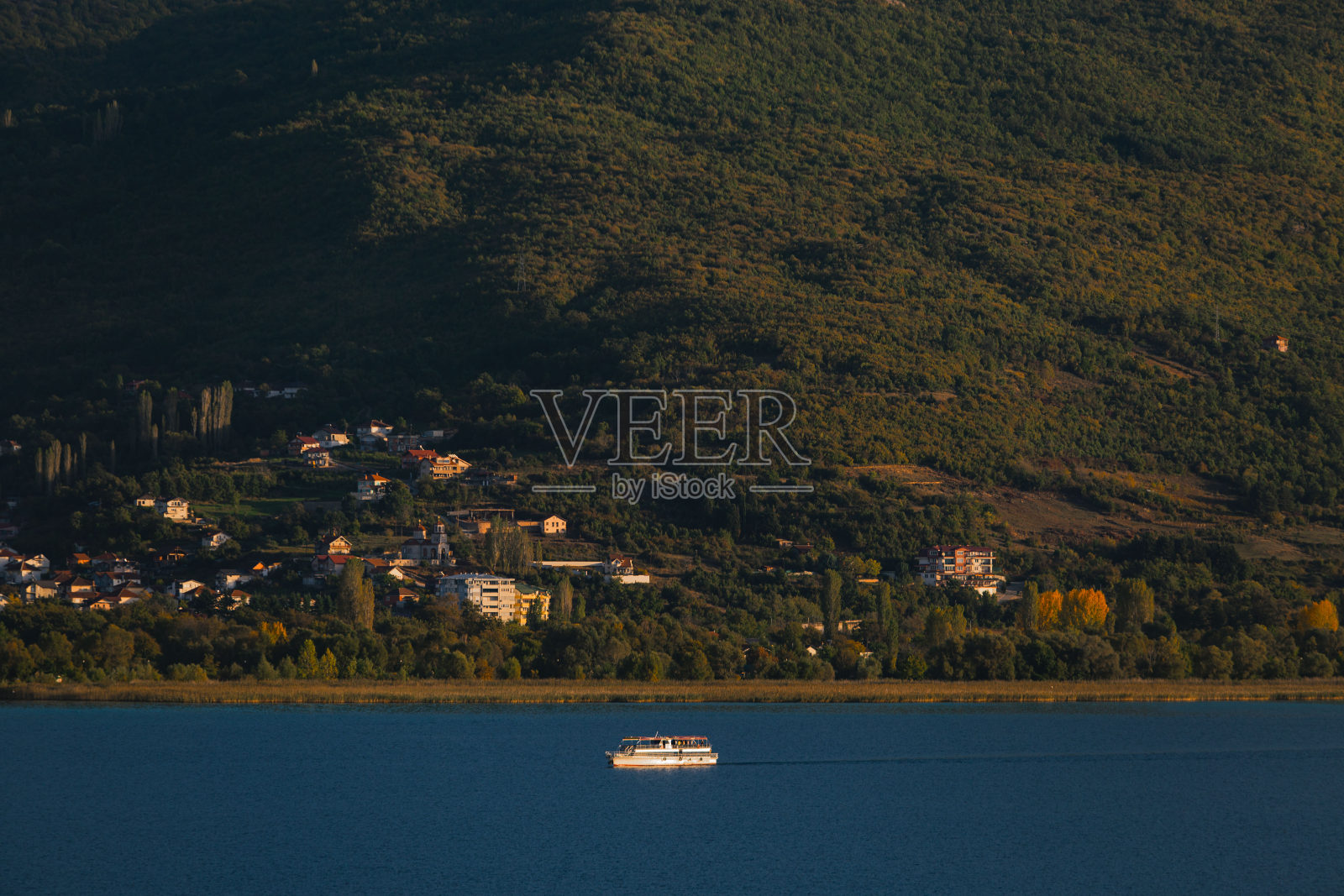一座绿色的大山，有房子和一艘大船照片摄影图片