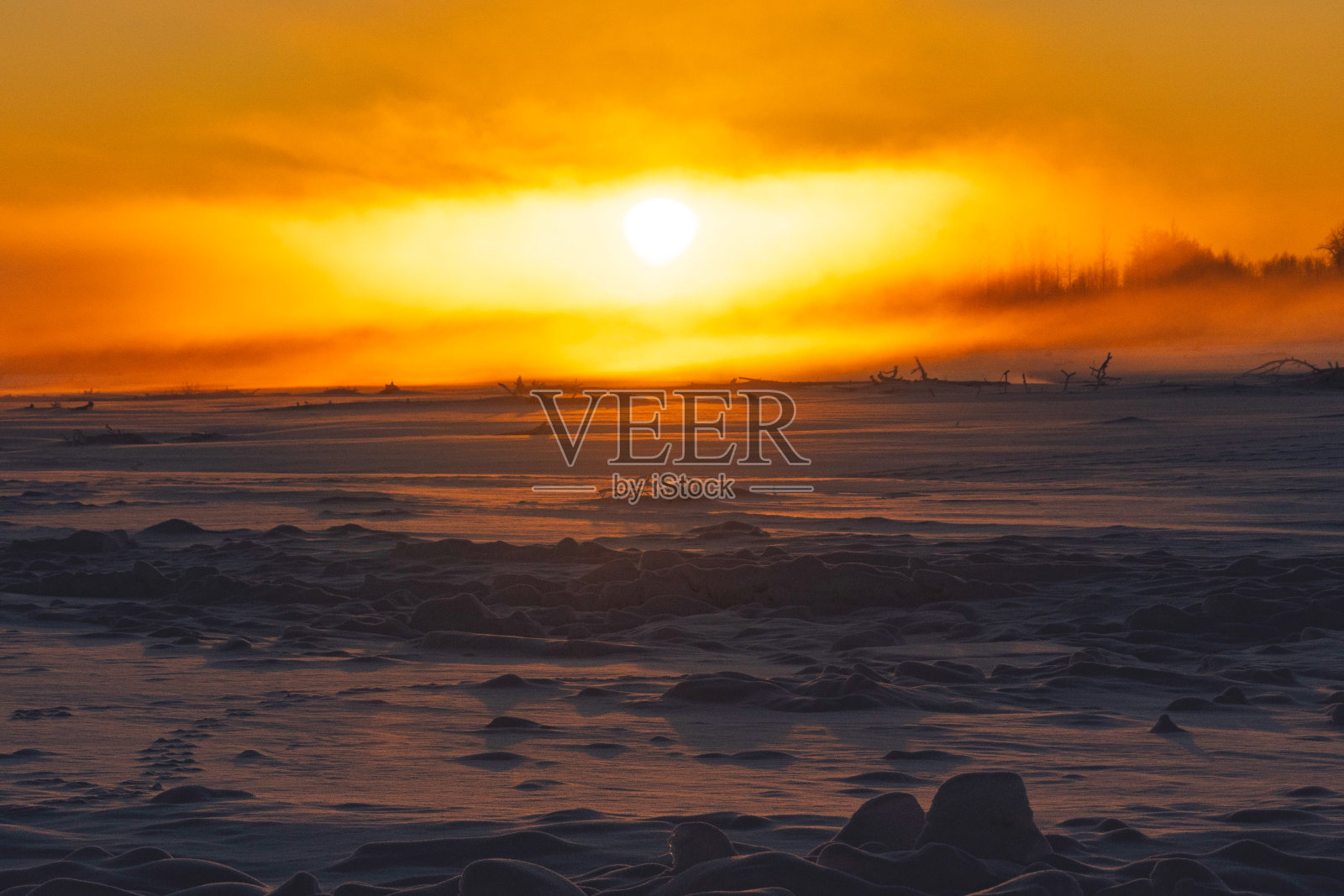 太阳落在阿拉斯加结冰的河流上照片摄影图片