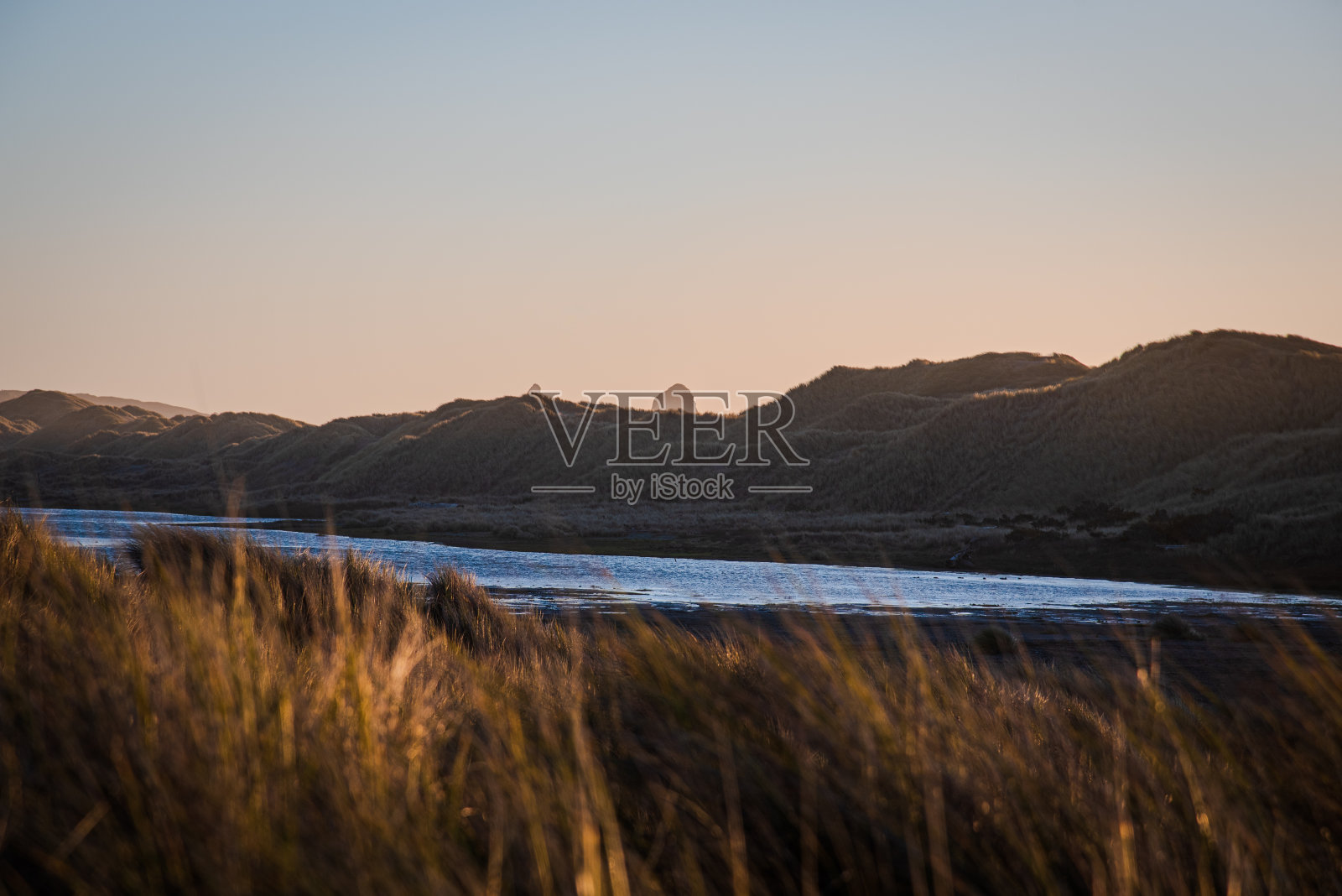 日落时远处沙滩沙丘上的岩石照片摄影图片
