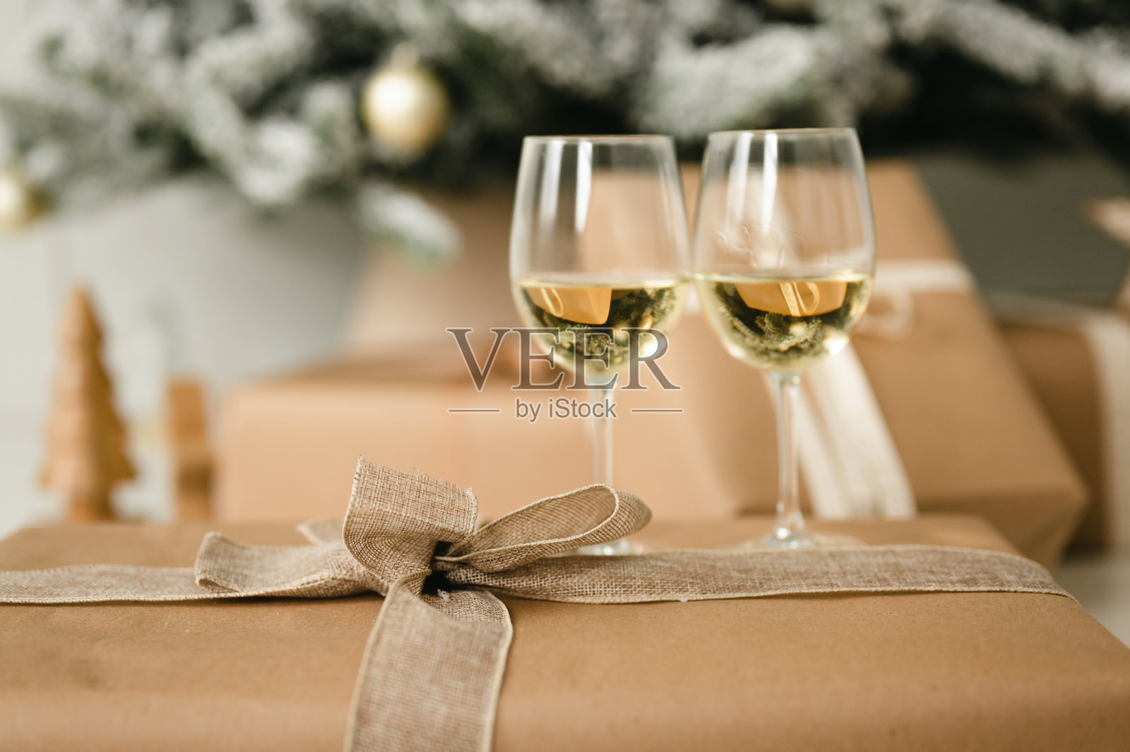 礼物用彩带和两个酒杯包在圣诞树旁照片摄影图片
