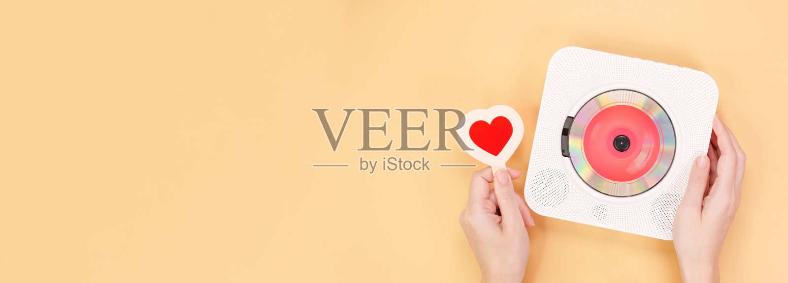 手拿白色cd播放机与红色光盘和心形礼品卡在黄色背景。爱情的音乐，情人节的祝福，复古的情歌，文字的空间。照片摄影图片