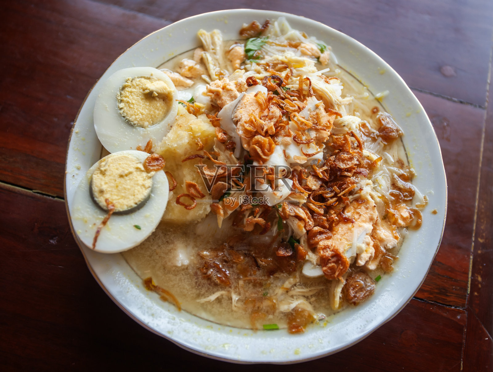 Soto Banjar，来自南加里曼丹Banjarmasin的传统食物。新鲜的汤上面有鸡肉和鸡蛋，和米饭或年糕一起吃。照片摄影图片
