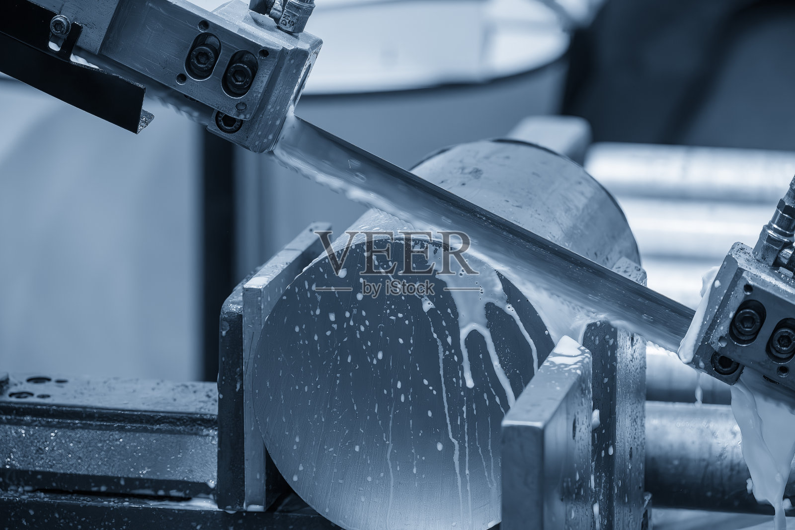 带锯切割机用冷却液法切割金属轴类零件。照片摄影图片