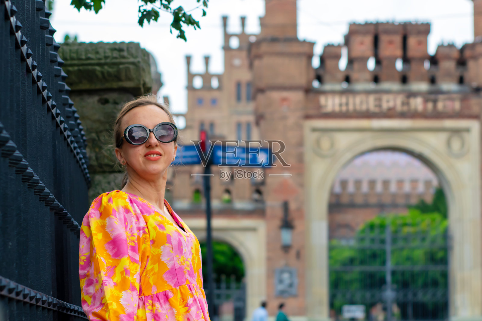 一个身穿橘黄色火红长裙的女孩走在一座古城里。照片摄影图片