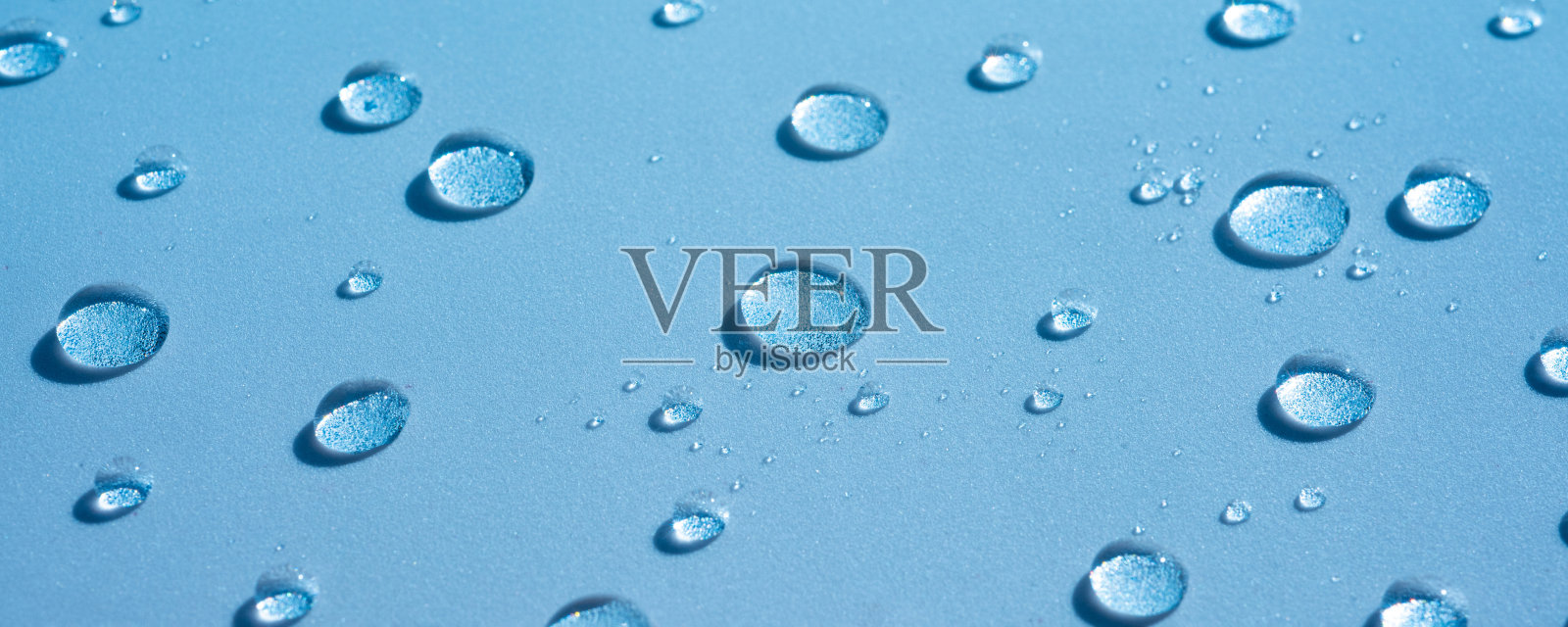 水的背景与水滴在一个蓝色的表面，潮湿的图案照片摄影图片