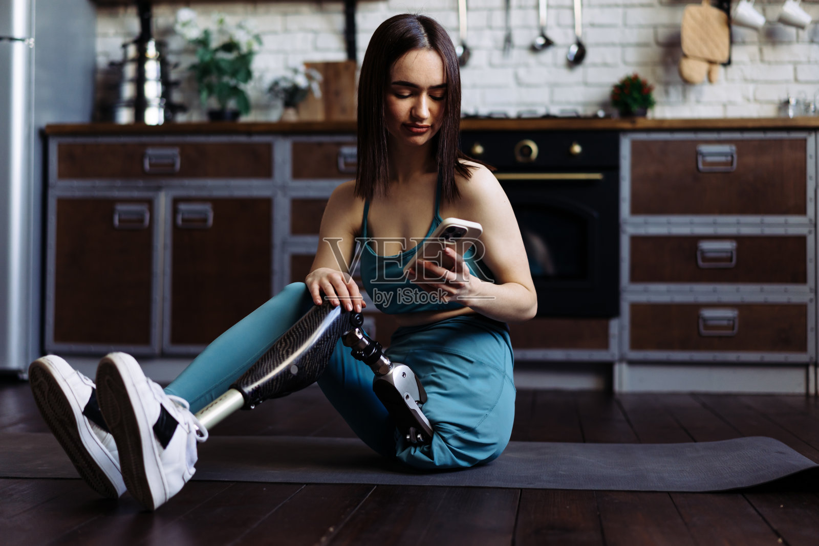 年轻的残疾妇女在训练后坐在垫子上放松照片摄影图片