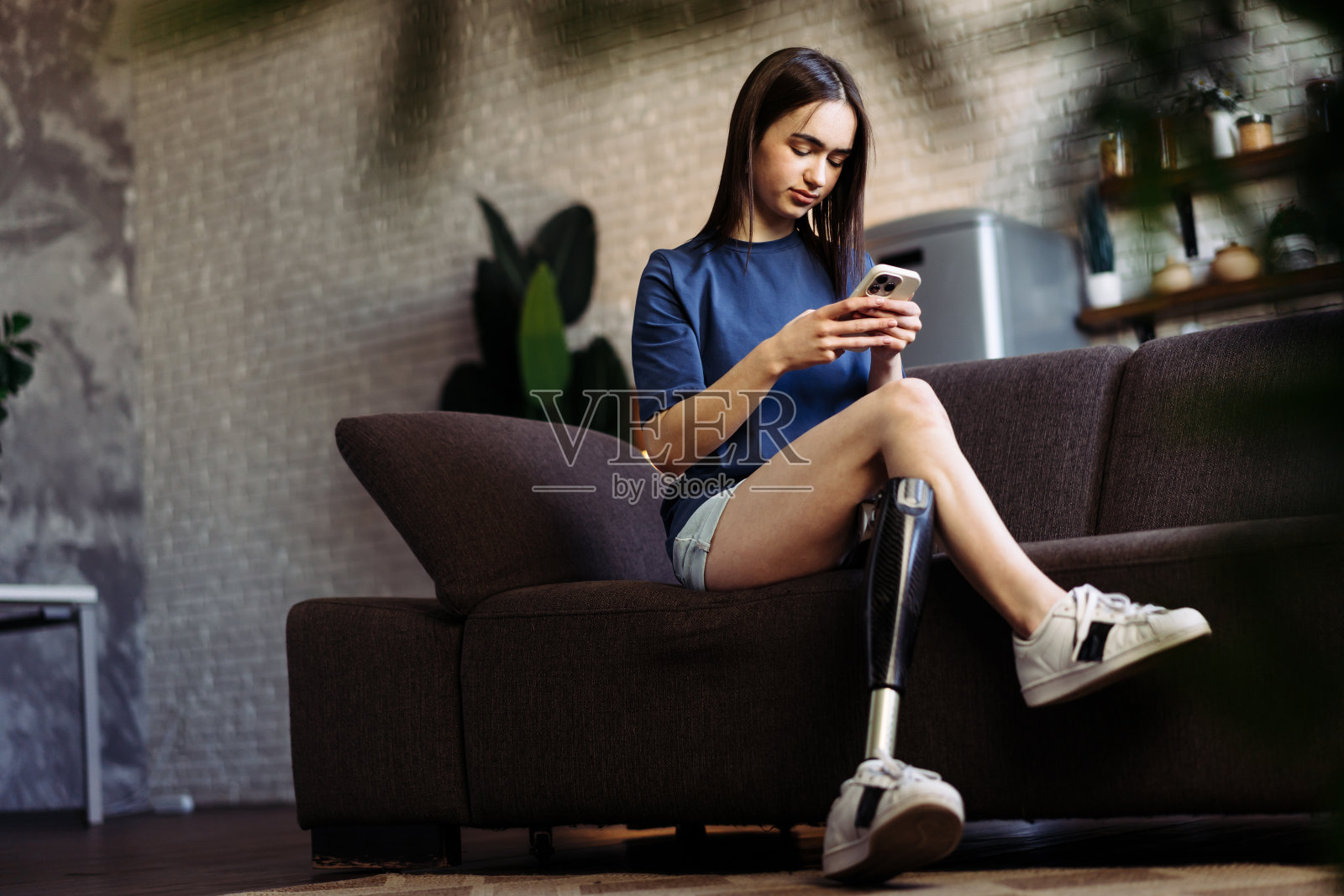 一位残疾妇女坐在沙发上用手机打字照片摄影图片