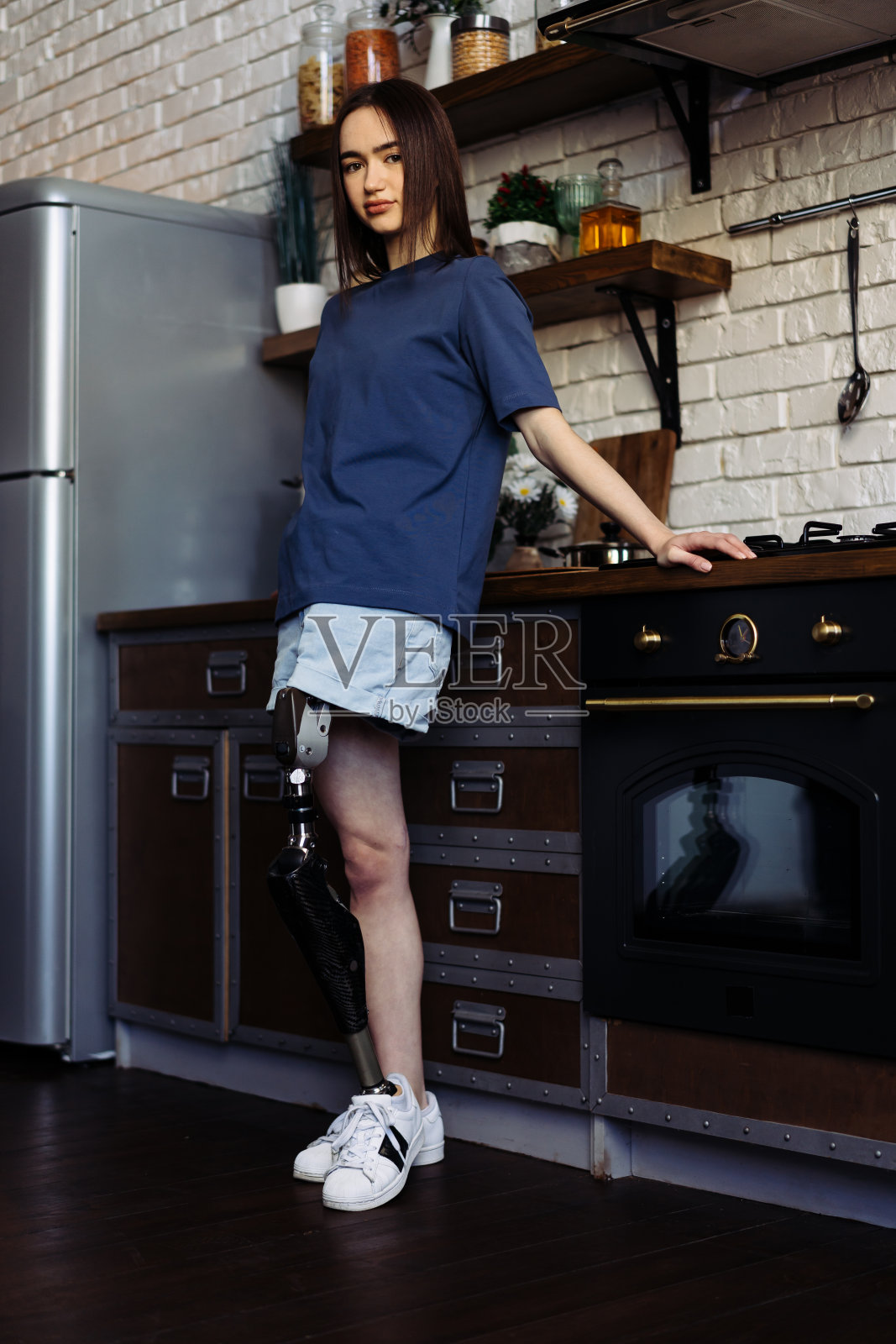 有假肢的女士双臂交叉站在厨房里照片摄影图片