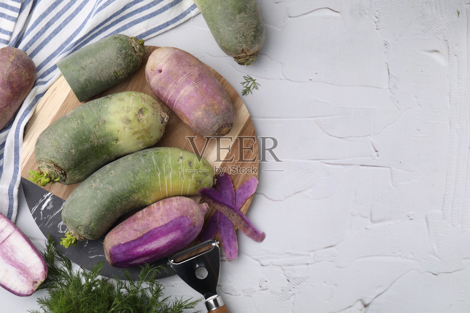 白萝卜，莳萝和削皮器放在白色有纹理的桌子上，平铺。文本空间照片摄影图片