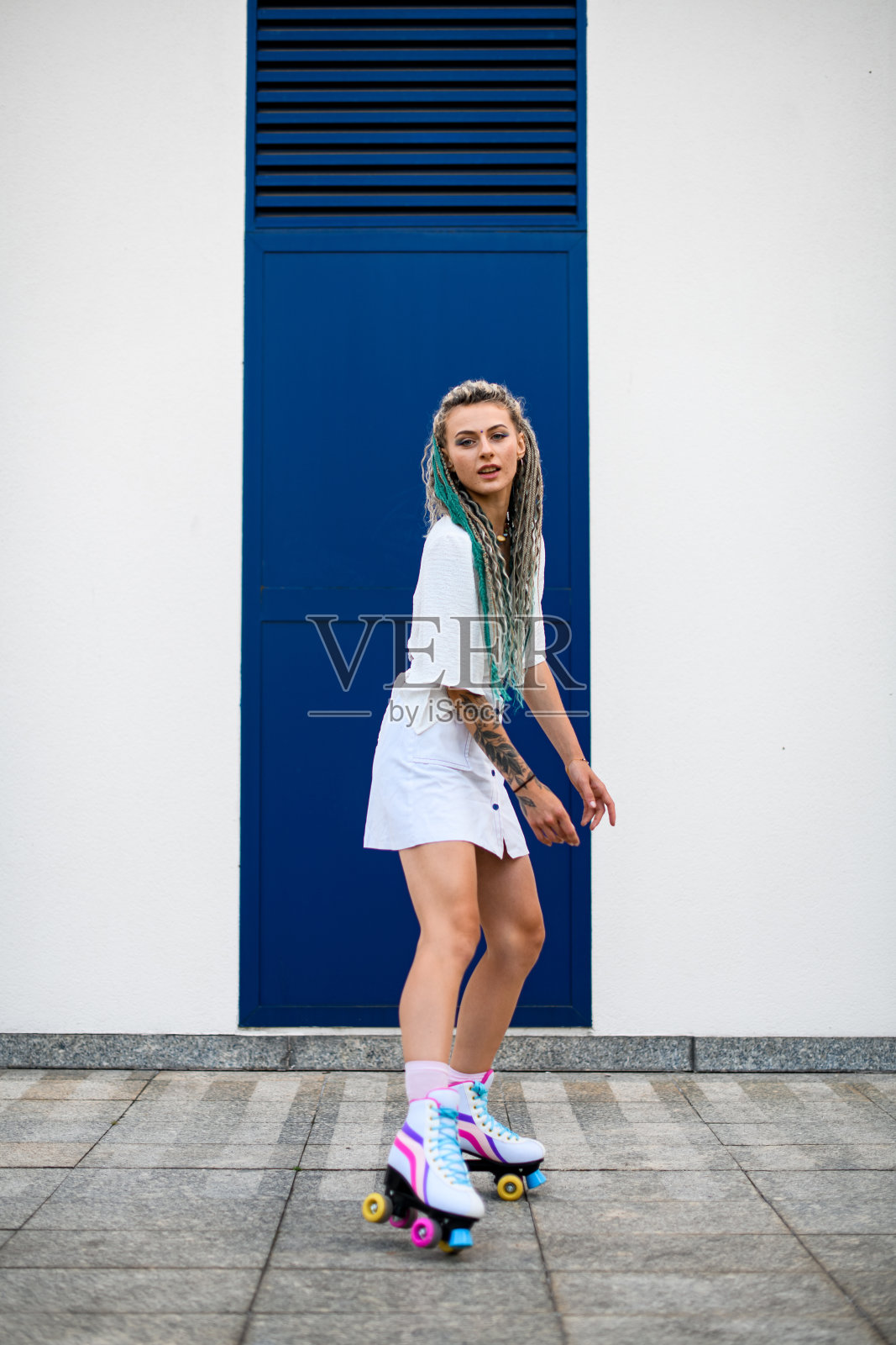 全长照片的妇女与复古轮滑鞋外对白色墙壁的背景照片摄影图片