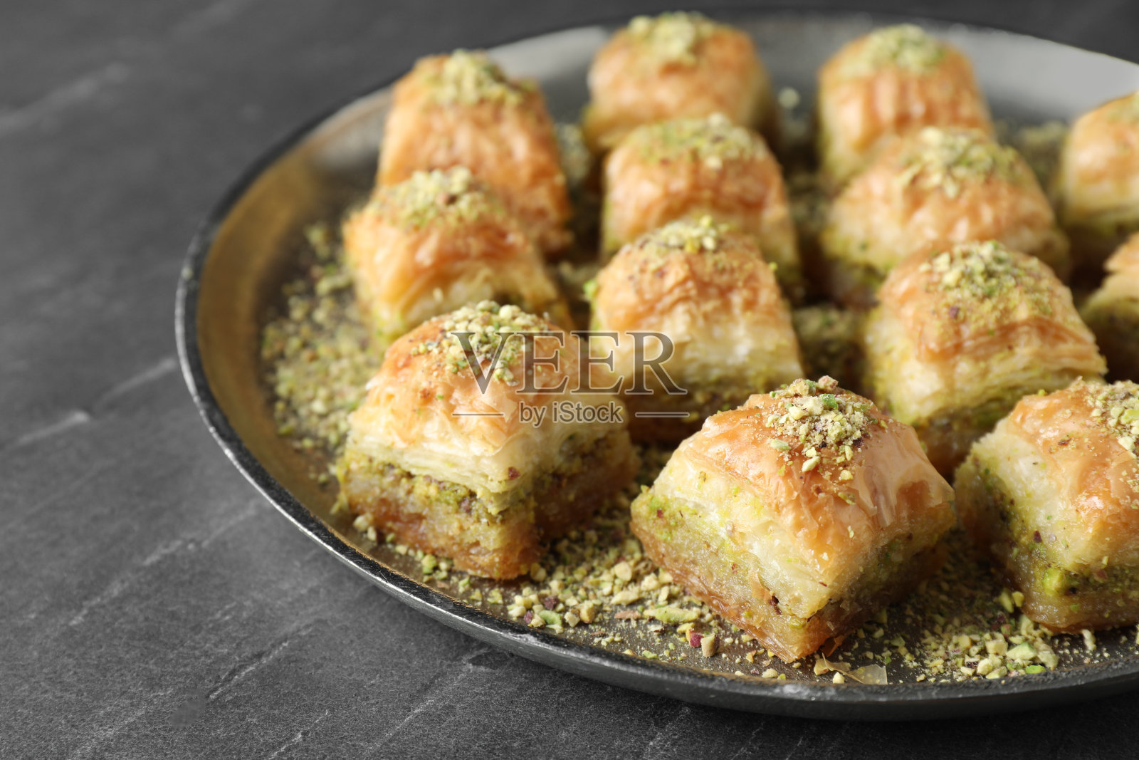 灰色的桌子上放着美味的新鲜果仁蜜饼和切碎的坚果，特写。东部的糖果照片摄影图片