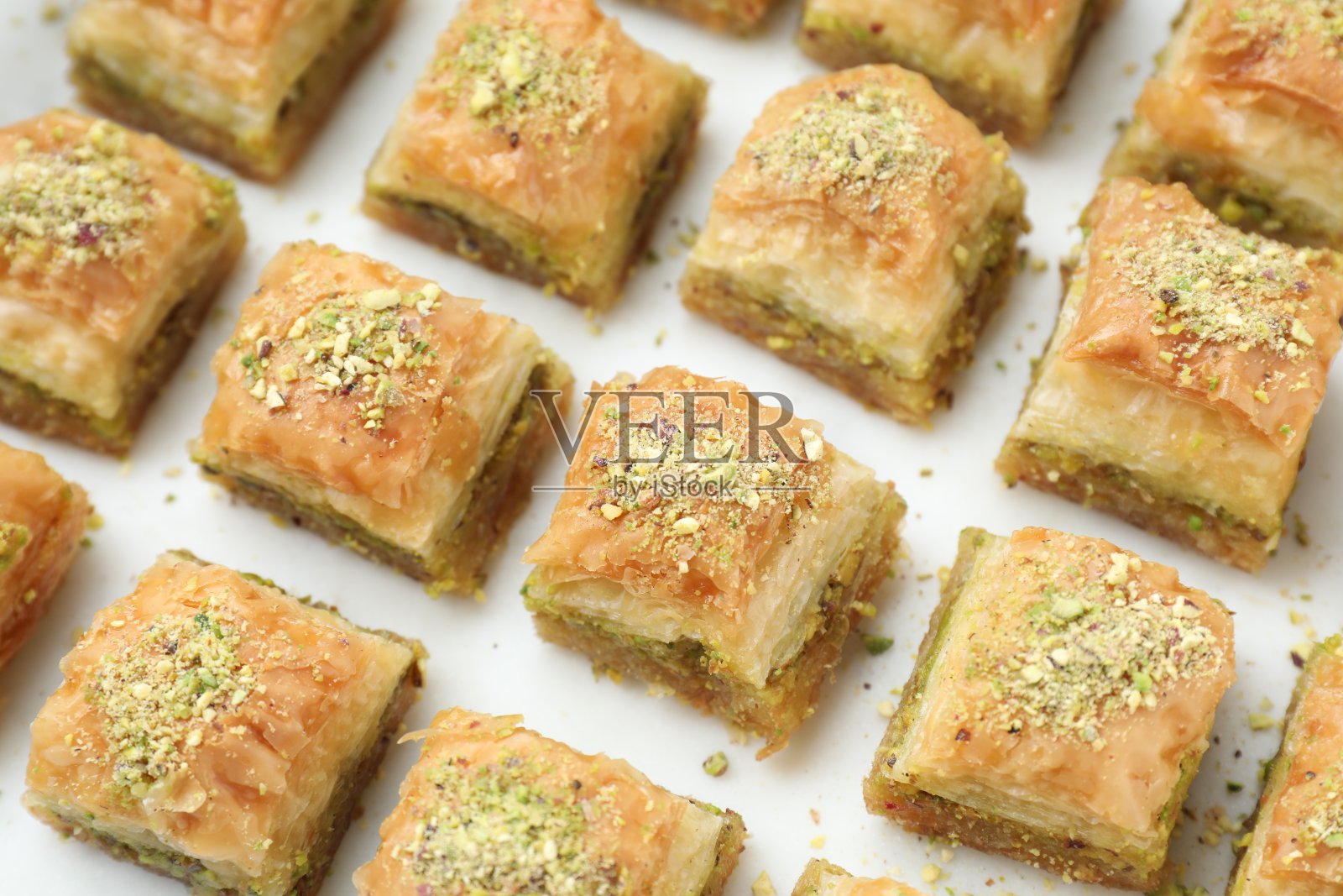 白色桌子上美味的新鲜果仁蜜饼和切碎的坚果，特写。东部的糖果照片摄影图片