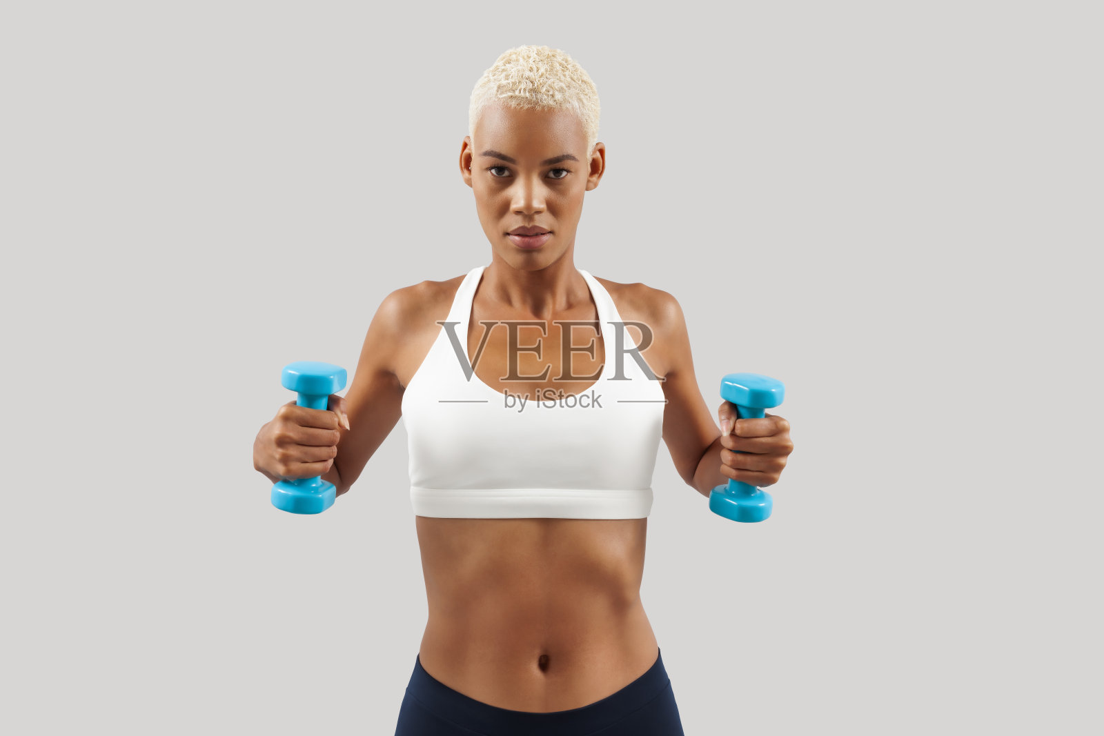 拉美女子举哑铃，年轻女运动员进行健身锻炼，从事体育活动，增进健康和体质。女运动员在训练，孤立的灰色背景照片摄影图片