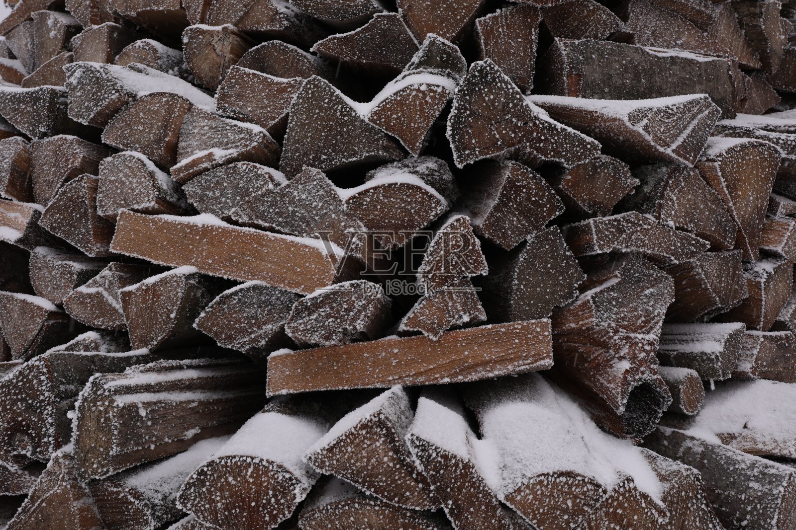 堆积的柴火与雪和白霜为背景，特写照片摄影图片