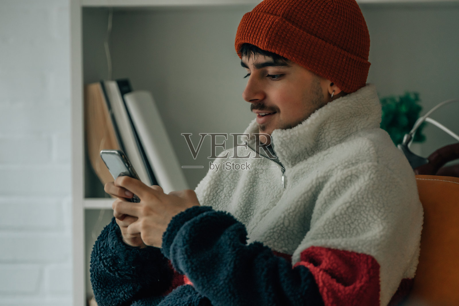 年轻人在家用手机取暖照片摄影图片