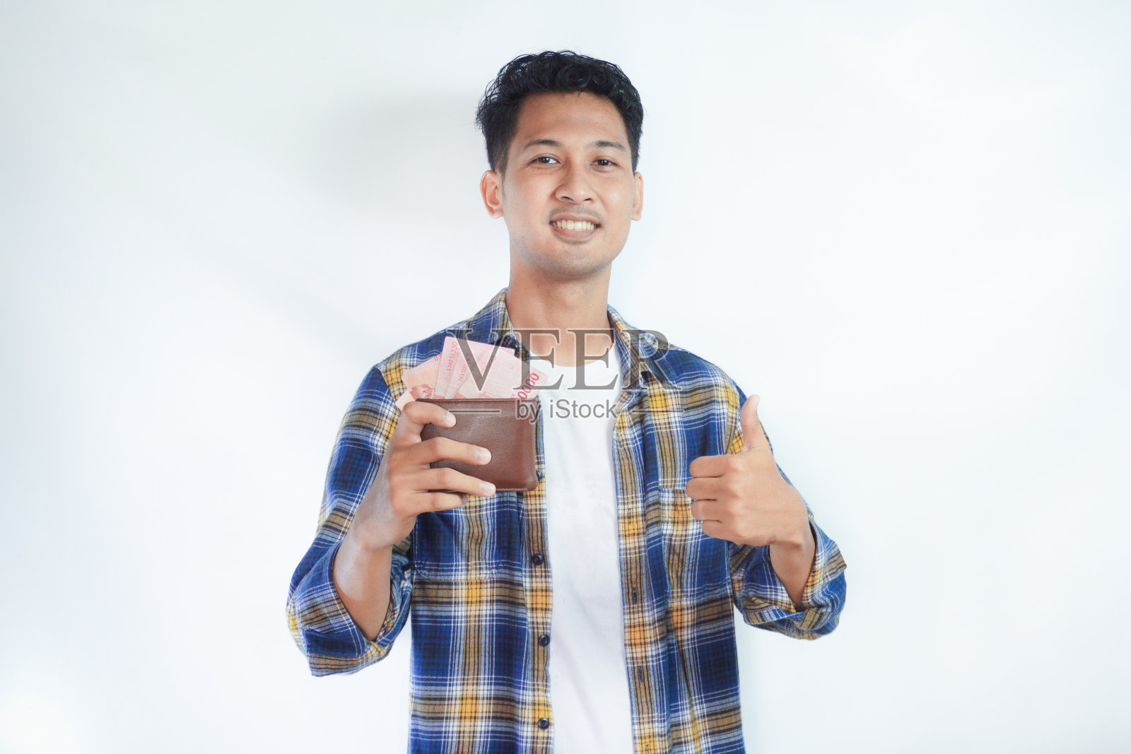 亚洲成年男子举着钱竖起大拇指的特写，脸上露出快乐的表情照片摄影图片