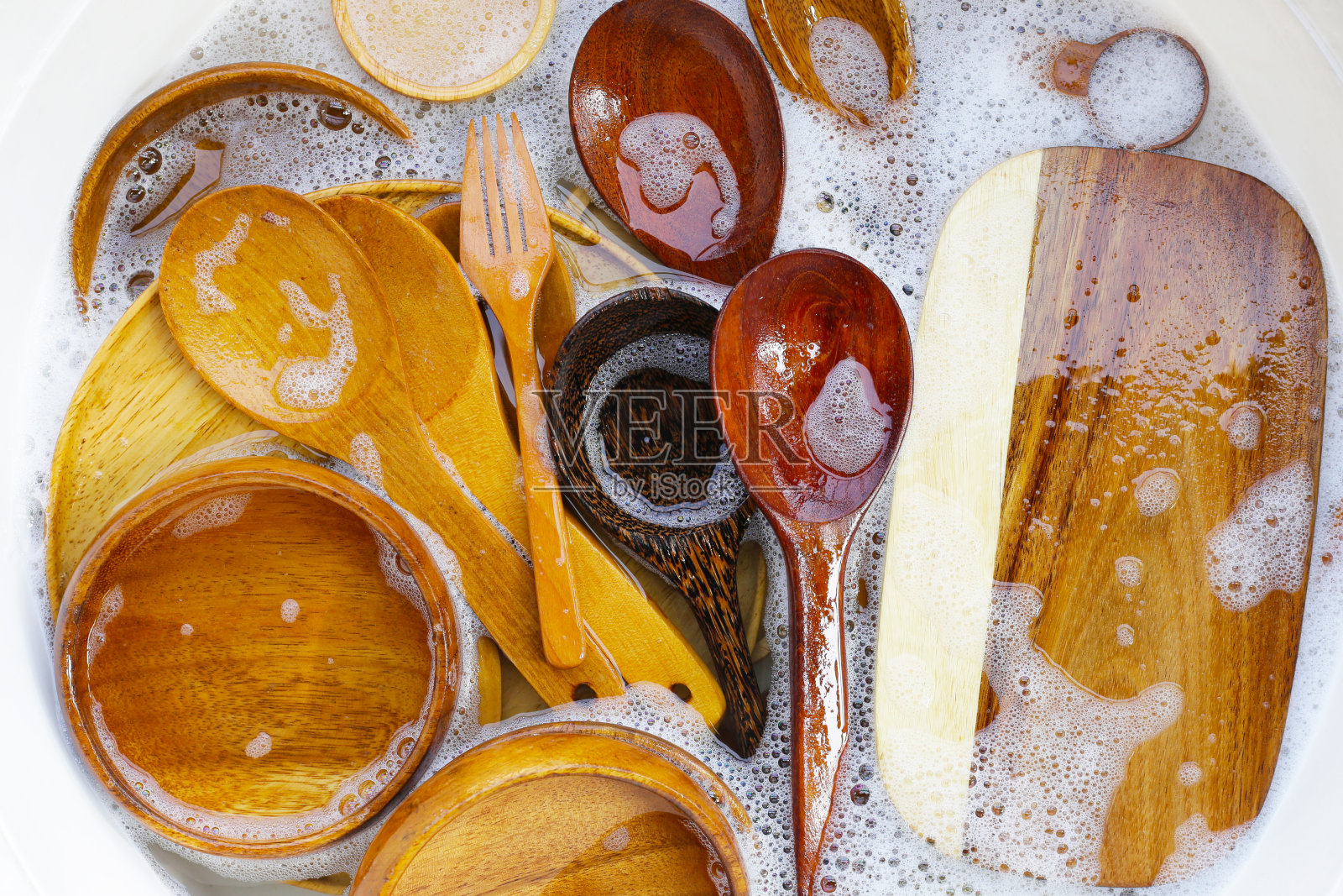 木制厨具浸在水中，还有洗碗液的气泡照片摄影图片