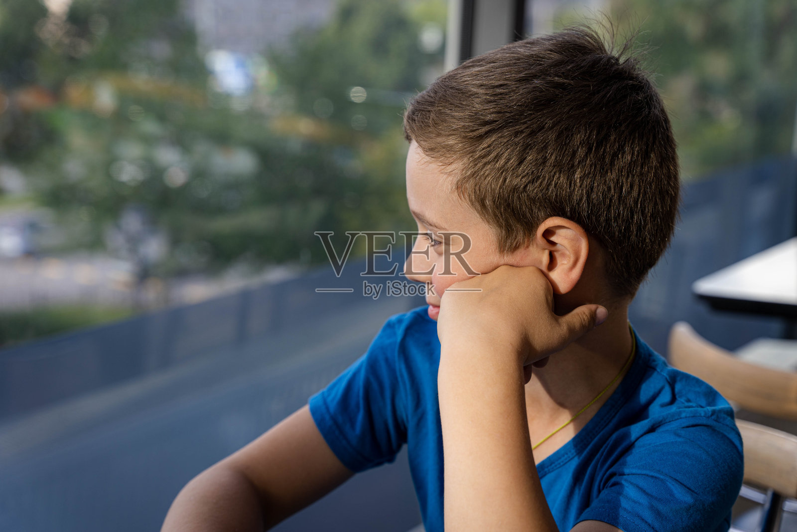 一个迷人的白人男孩坐在舒适咖啡馆的桌子旁照片摄影图片