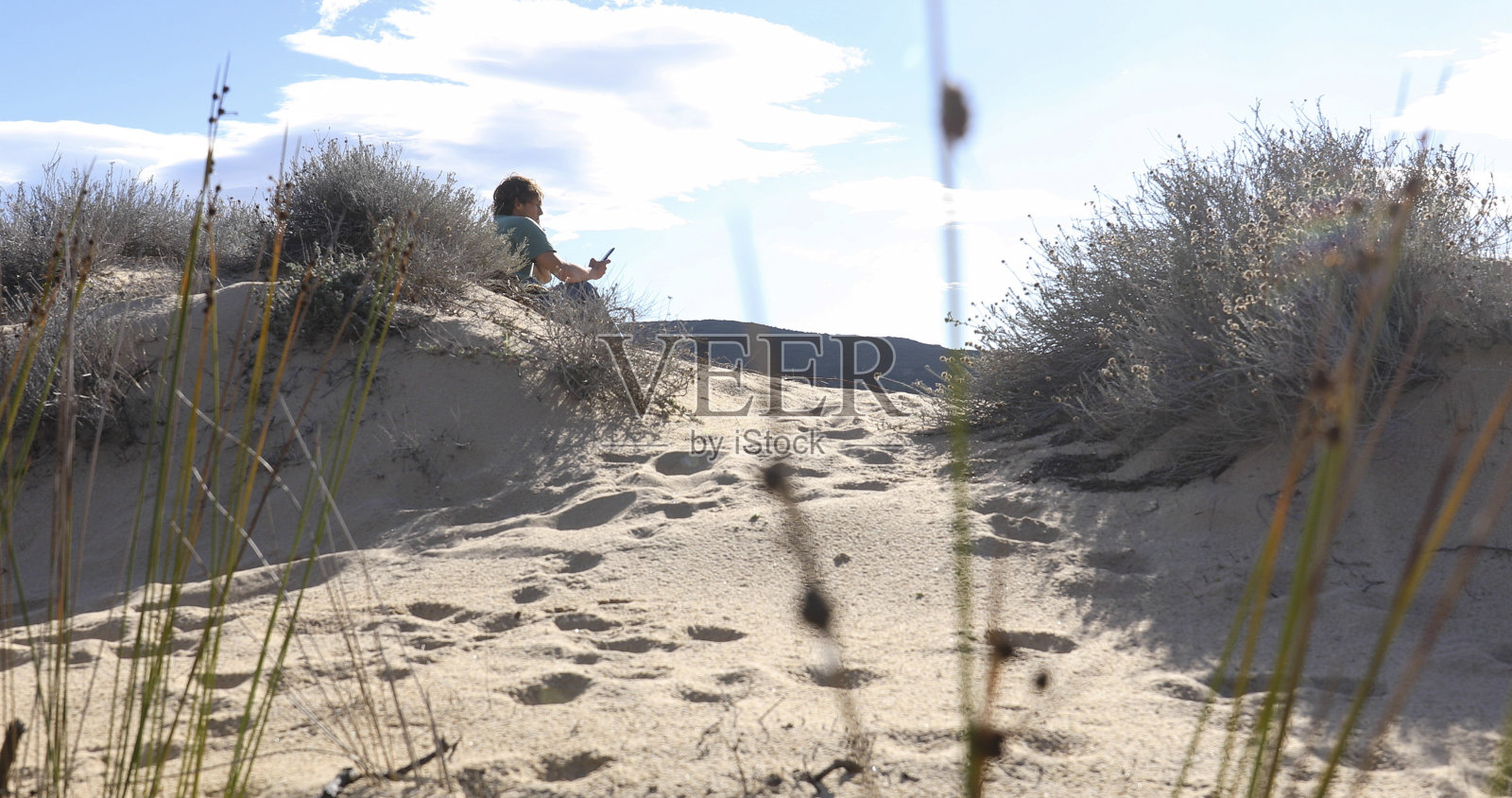 年轻人在海边玩手机照片摄影图片