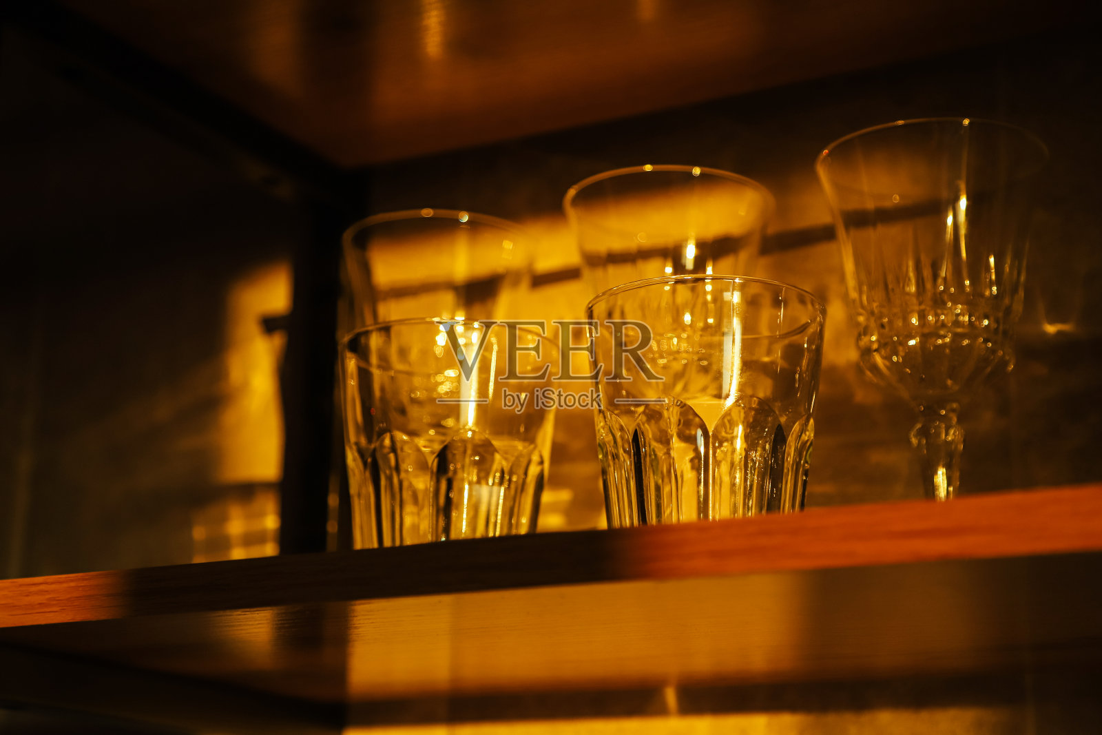 在夕阳的余晖中，家庭厨房的木架子上摆放着水杯和酒杯照片摄影图片