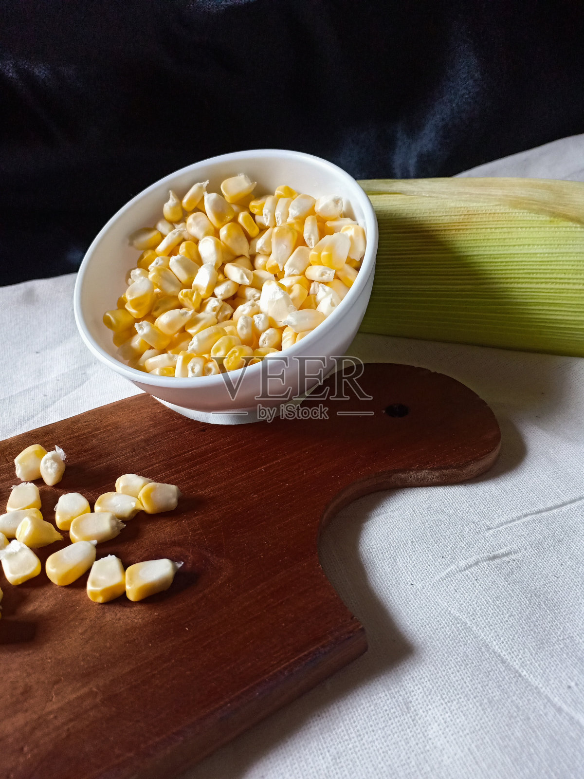 白色的桌子上放着剥了皮的玉米照片摄影图片