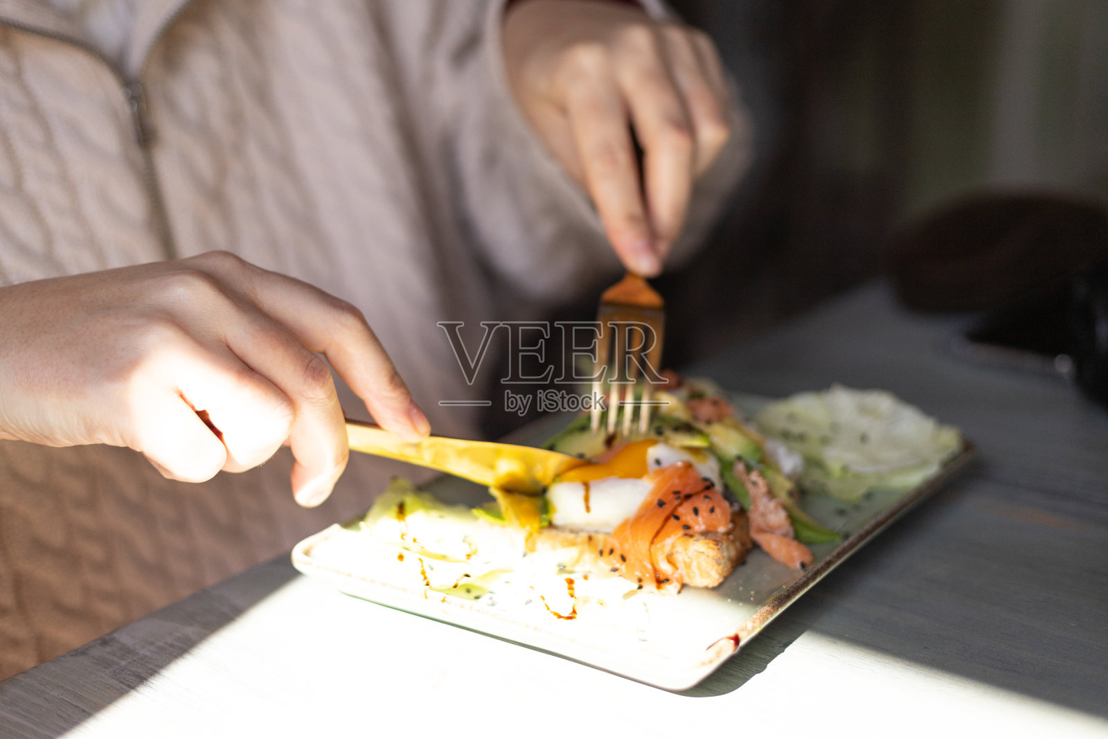 女孩吃烤面包配鲑鱼和鸡蛋，一个年轻女子的手照片摄影图片