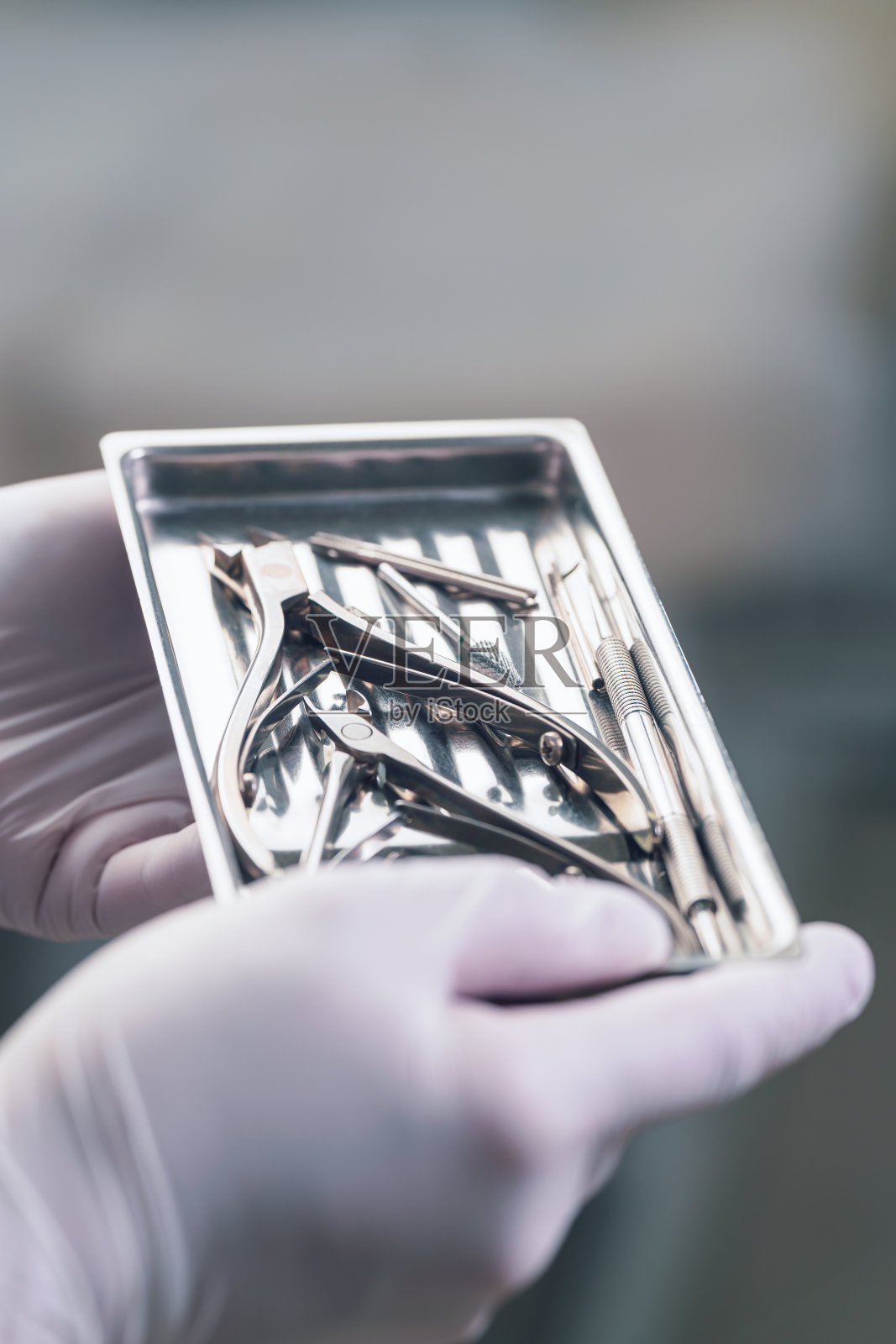 一个戴着手套的女孩拿着一个装有消毒医疗器械的托盘进行足疗照片摄影图片