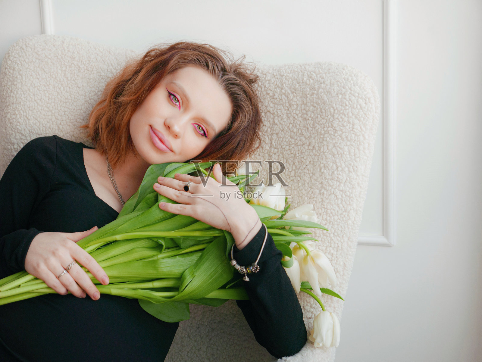 一名孕妇，梳着发型，脸上化着妆，穿着黑色紧身衣，上面有白色郁金香照片摄影图片