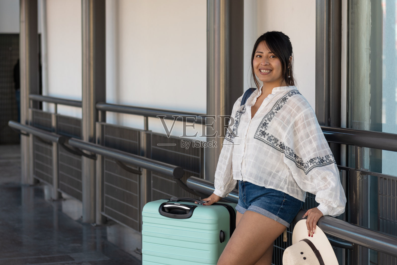 图为一名独自旅行的26岁女乘客带着行李箱在车站候车照片摄影图片