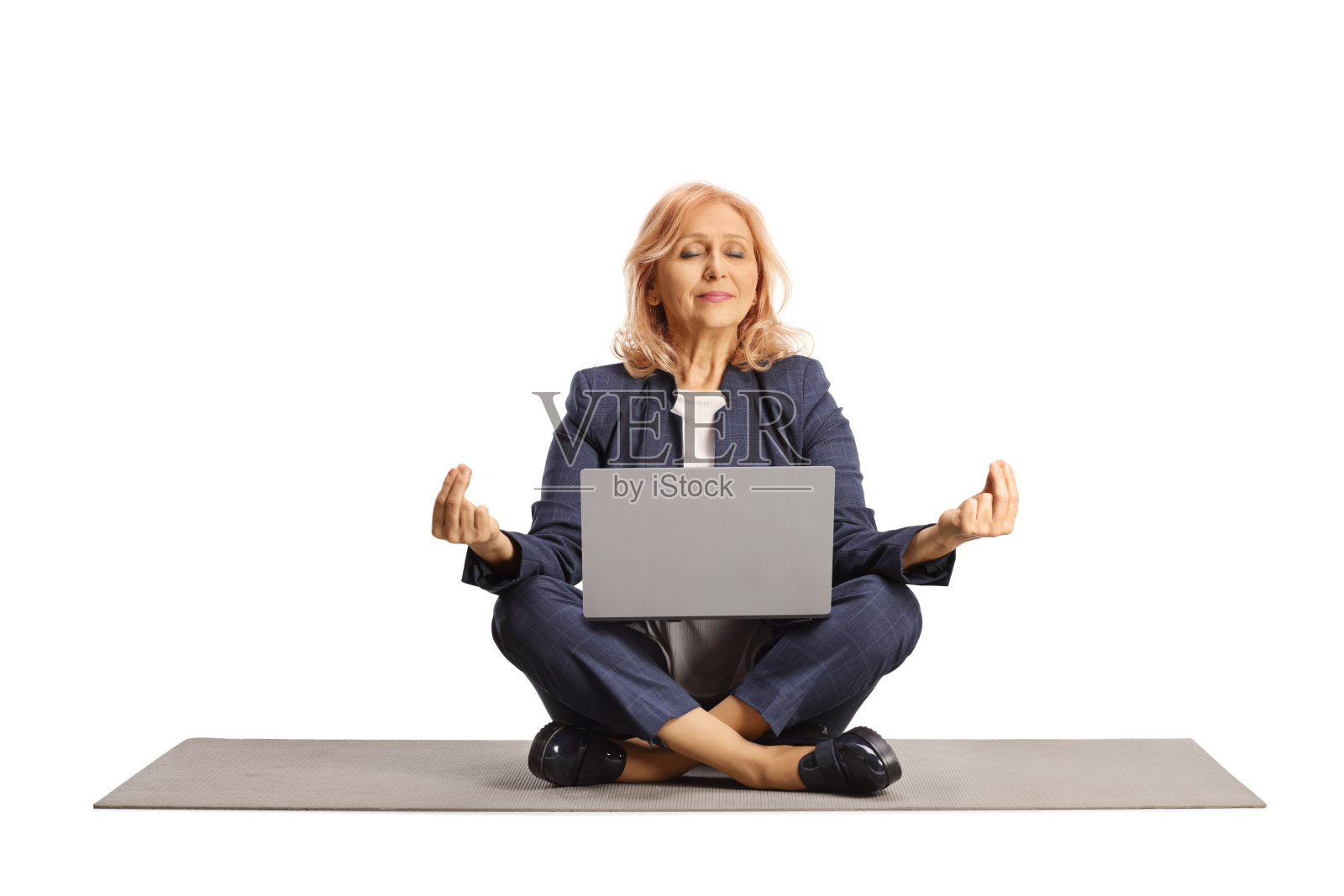 拿着笔记本电脑坐在运动垫上做冥想姿势的女商人照片摄影图片