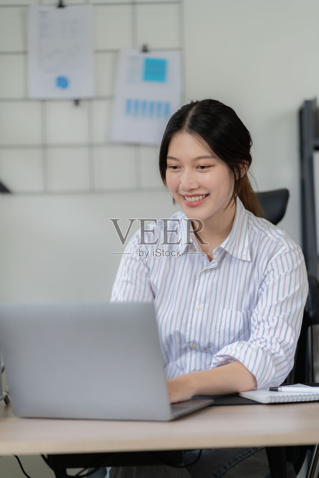 专业的亚洲女性会计专注于她的销售账目，使用计算器和笔记本电脑在她的办公桌上分析报告和业务文件。照片摄影图片