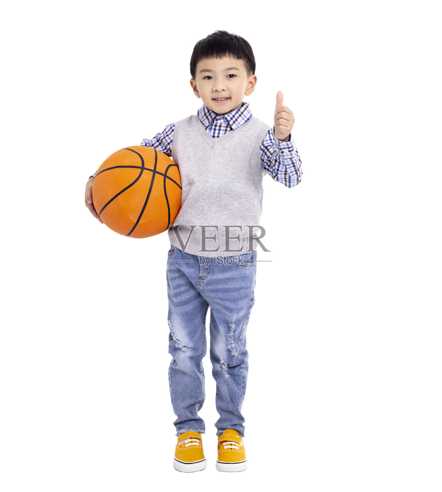 快乐的亚洲男孩拿着一个篮球，在白色的背景上竖起大拇指照片摄影图片