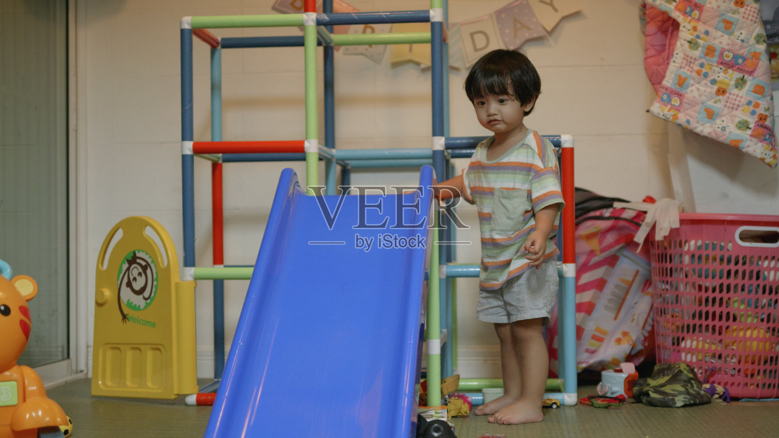 亚洲男孩喜欢玩卡车汽车滑滑梯。家里的操场。照片摄影图片