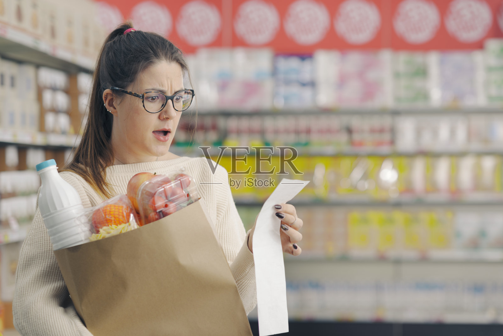 一位女士在超市检查一张昂贵的购物收据照片摄影图片