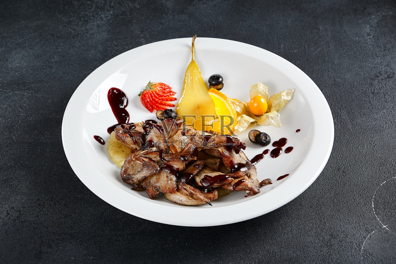 美味的照烧鸡翅与充满活力的水果搭配在有质感的黑色餐桌上。在烹饪呈现中，品味与优雅的交响乐照片摄影图片