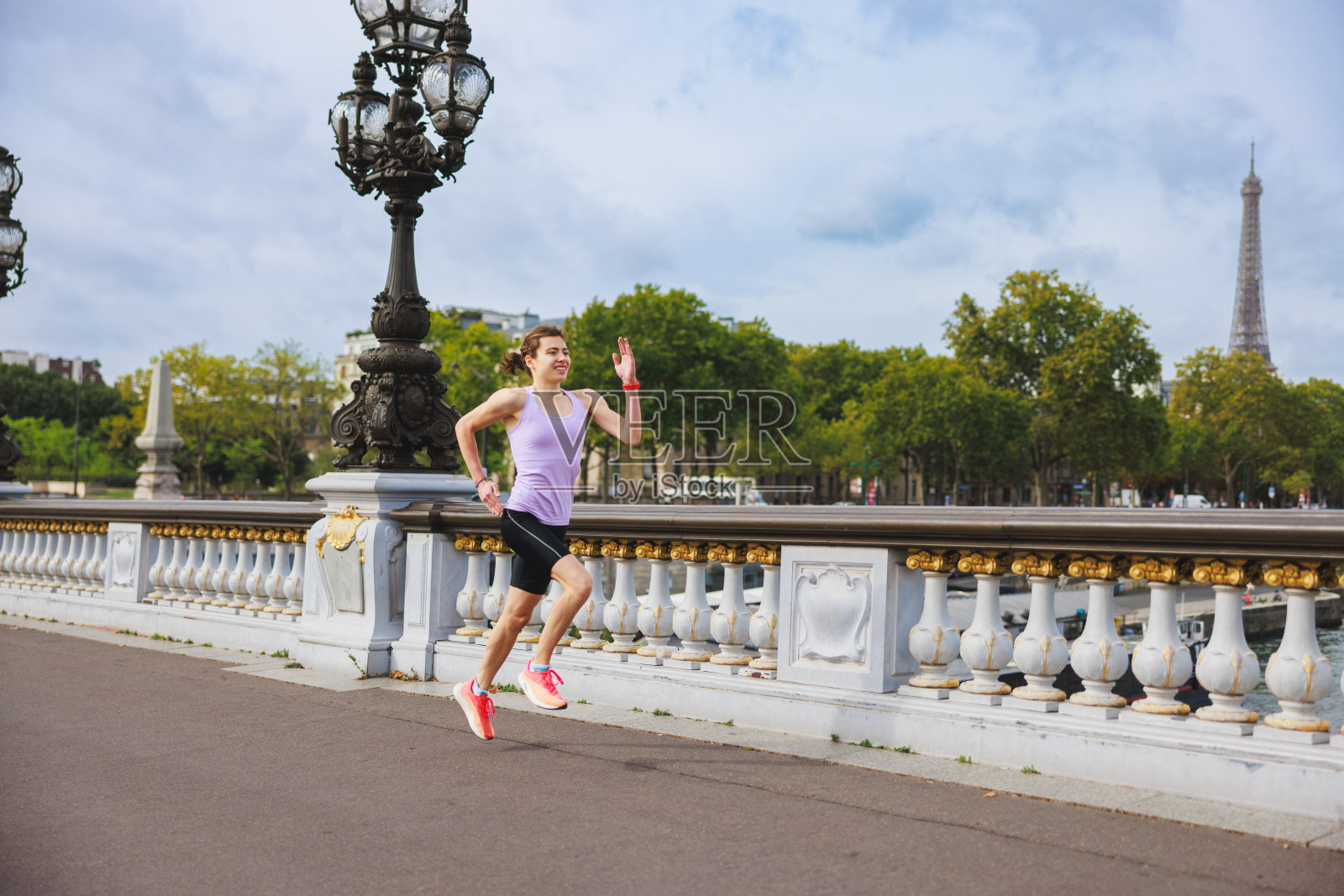 活跃的年轻女子穿着运动服，站在塞纳河上有栏杆的人行天桥上照片摄影图片