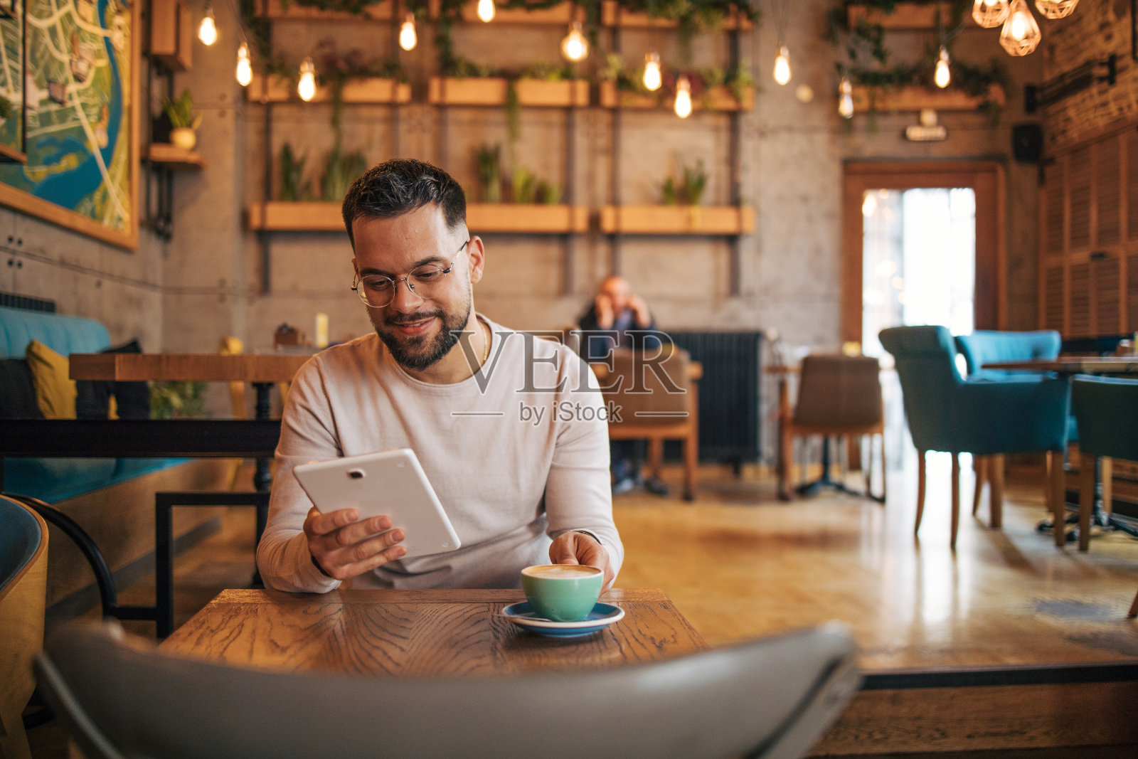 年轻人一边在咖啡馆喝咖啡，一边用着数码平板电脑照片摄影图片