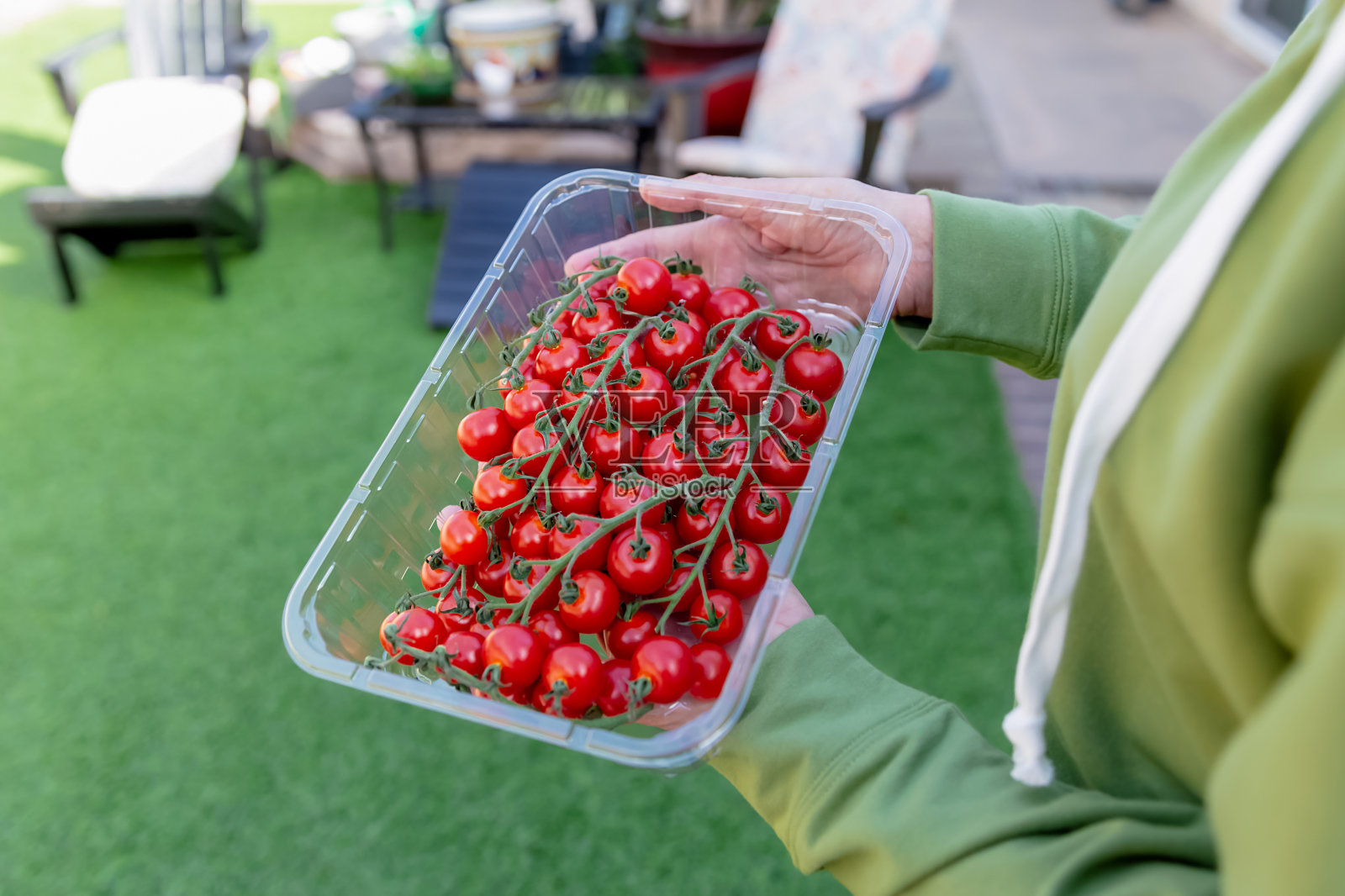 一个女人拿着一个装着西红柿的塑料容器照片摄影图片