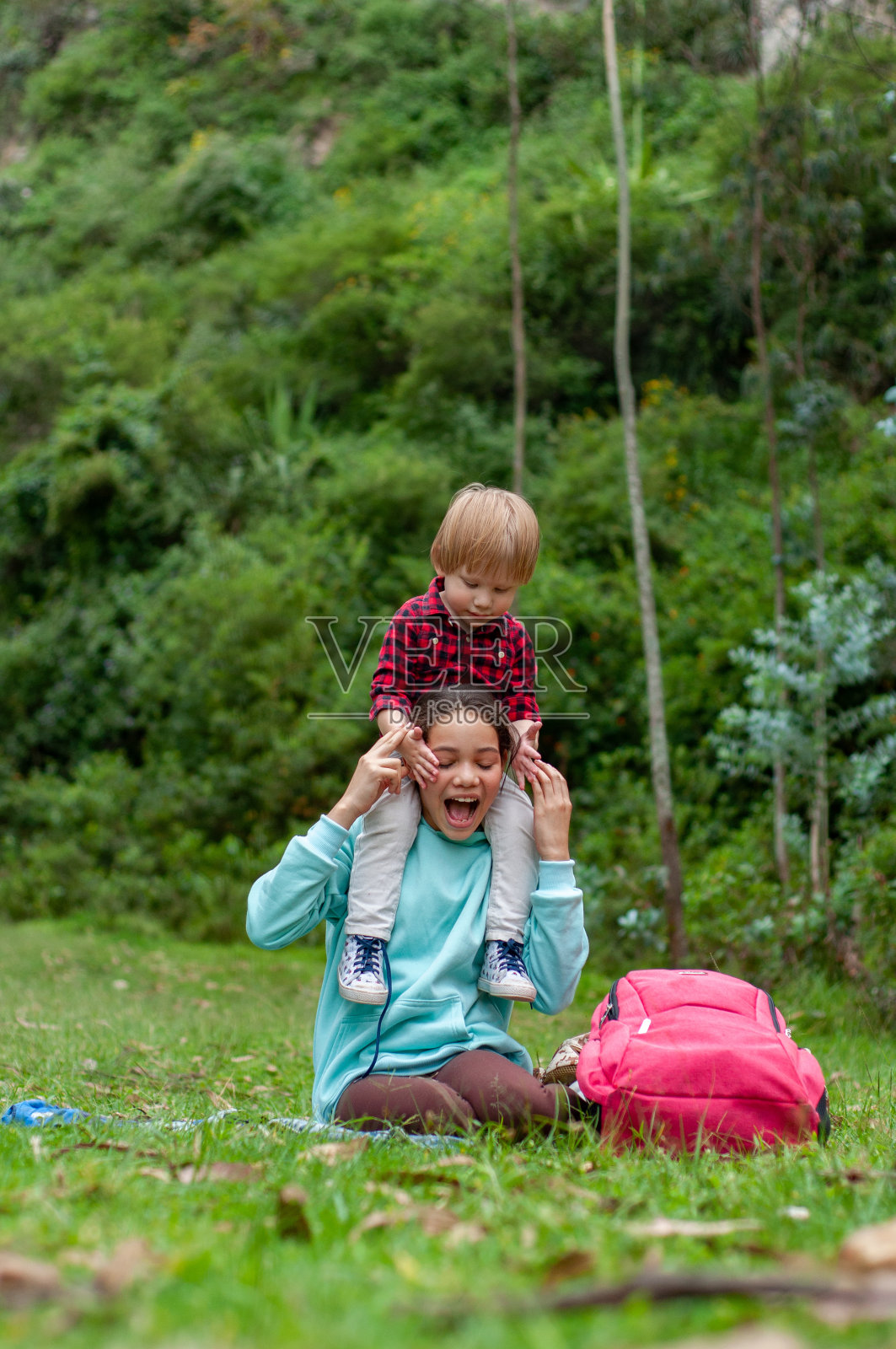 春天，女孩带着弟弟们在绿意盎然的公园里玩耍照片摄影图片
