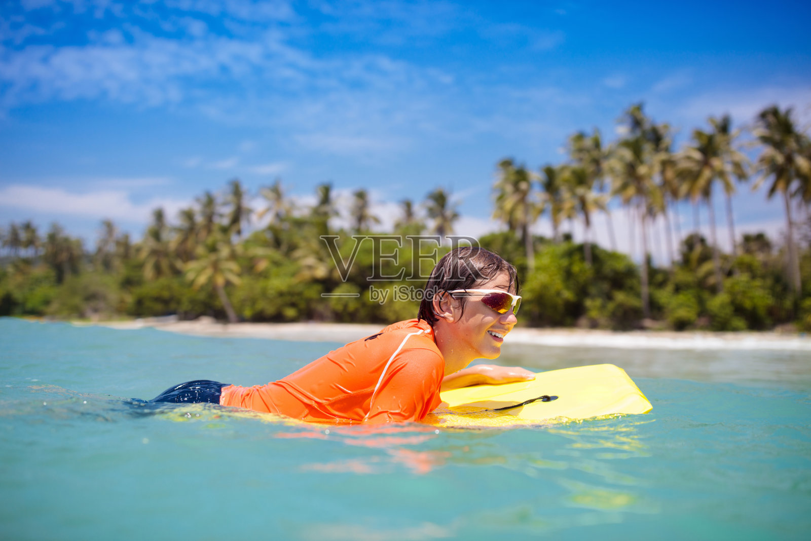 孩子们在热带海滩上冲浪。海里的冲浪者。照片摄影图片