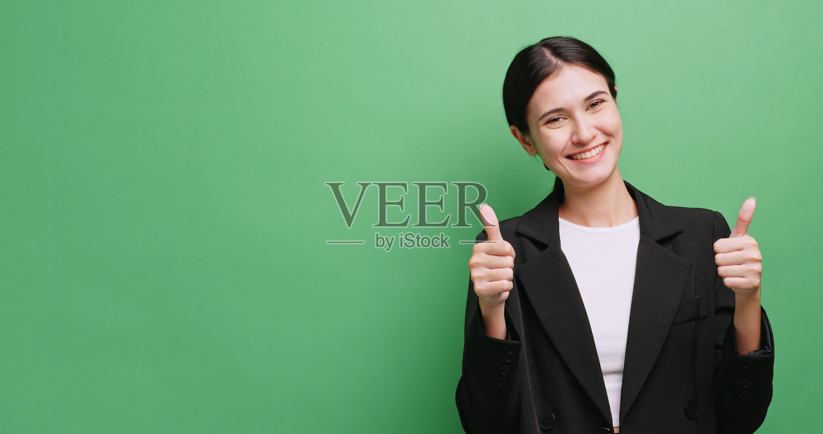 年轻的女商人对某件事表示赞同。孤立的绿色背景的工作室。照片摄影图片