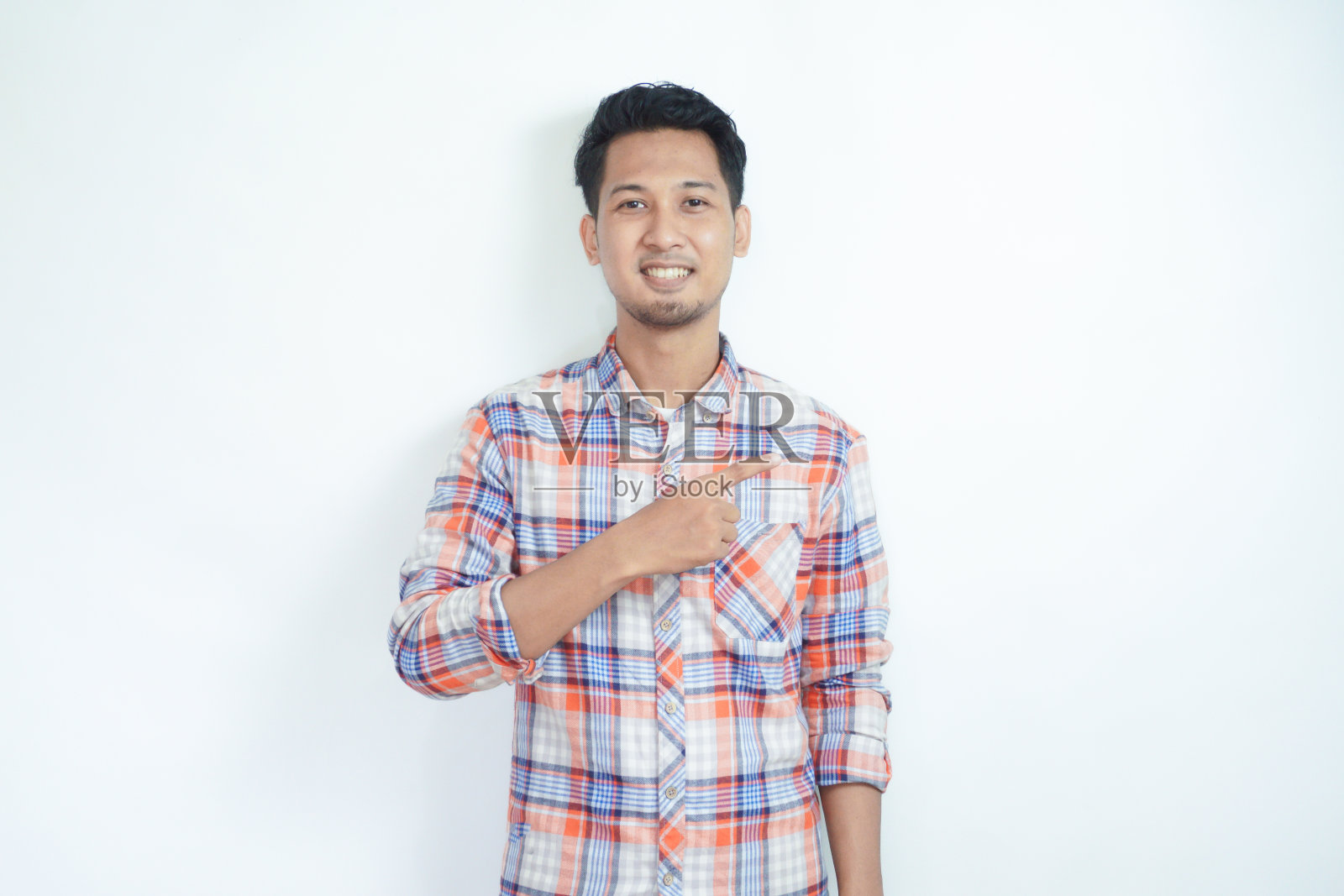 一个亚洲成年男子，右手指着左边，笑得很开心照片摄影图片