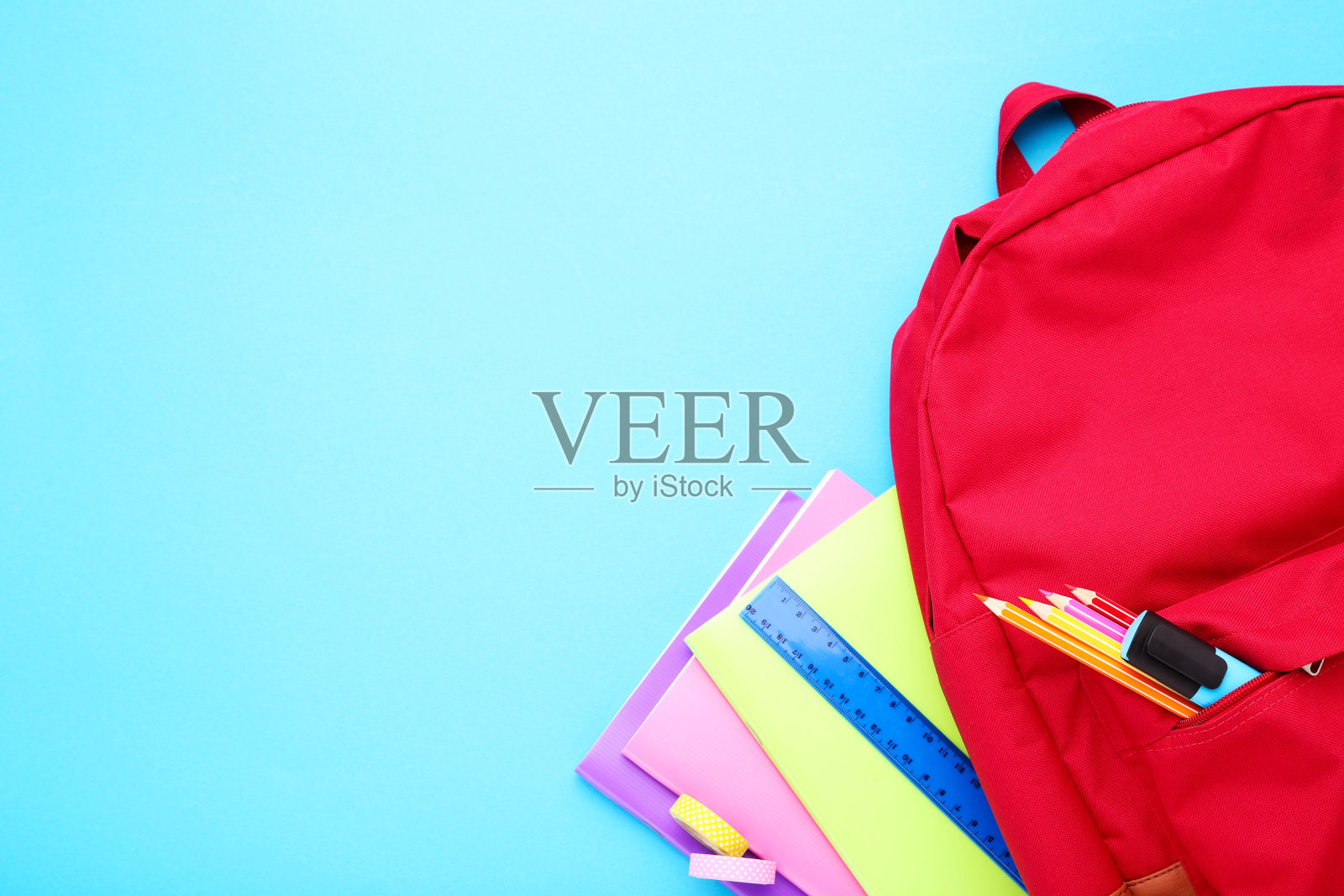 蓝色背景的书包里有学习用品照片摄影图片